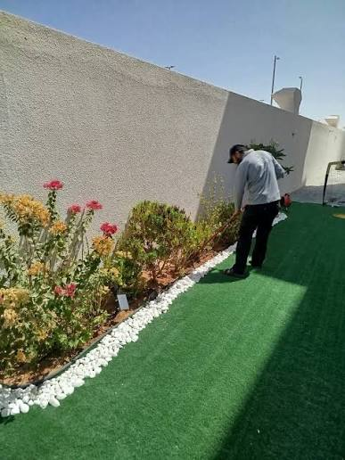 Garden beds with white pebble edging beside a lawn in Dubai
